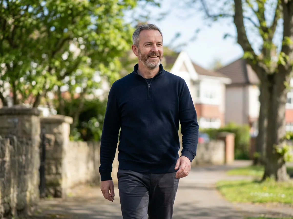 A man in his fifties walking briskly along a tree lined street in the morning